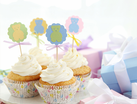 Cupcakes with little blue and pink gift boxes in background