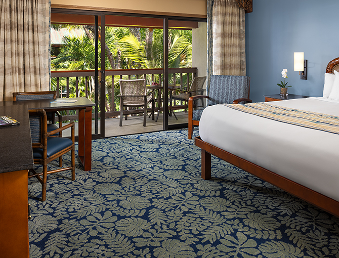 Interior view of the Catamaran Resort Room featuring one king bed, game table and private balcony overlooking the lush tropical gardens.