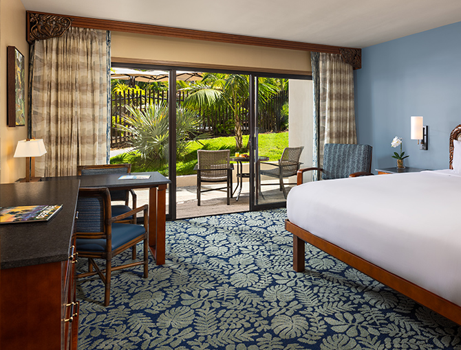 Interior view of the Catamaran Resort Room featuring one king bed, game table and private balcony overlooking the lush tropical gardens.