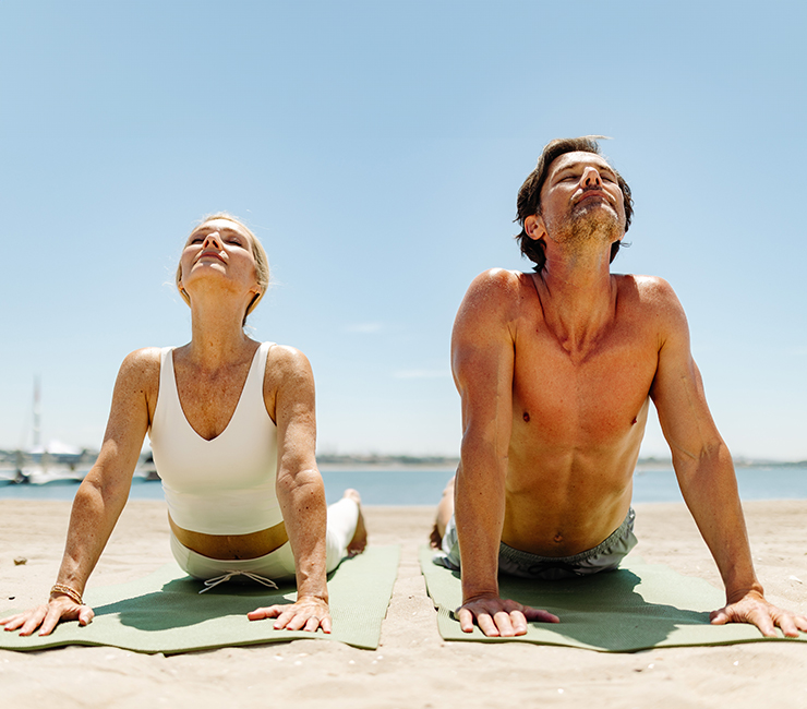 Couple doing yoga on the beach